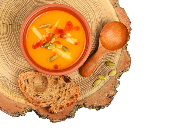 Bowl of pumpkin soup on wood cut over white