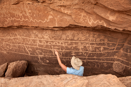 Along McElmo Creek in the Canyon of the Ancients National Monument on the Colorado and Utah border, a visitor enjoy the massive wall of petroglyphs including a bighorn sheep she points out which remains after hundreds of years.