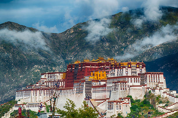 The Potala Palace in Lhasa, Tibet in October 1986 through prayer flags blowing in the wind. Early morning light. Potala Palace was the main residence of the Dalai Lama until 1959, when the 14th Dalai Lama went into exile after a failed uprising. Potala Palace is since 1994 on the UNESCO World Heritage List. Scan from 35mm slide film, with visible fim grain.