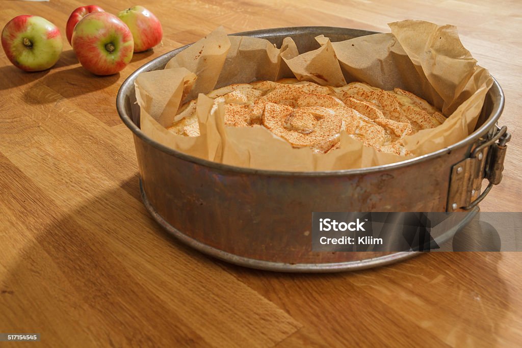 Baked apple pie and fresh apples Newly baked apple pie in a metal springform with apples lying next to it Apple - Fruit Stock Photo