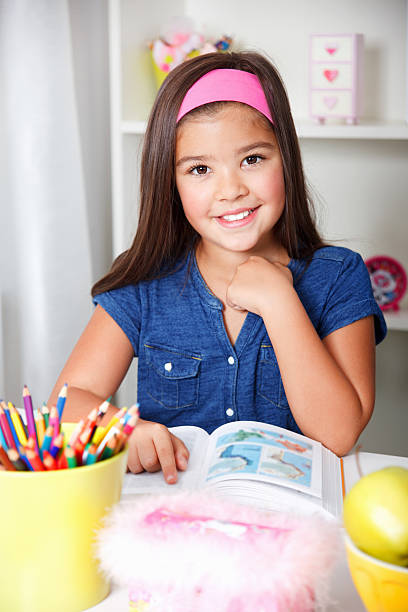 istock Beautiful young school girl reading a book 517155459