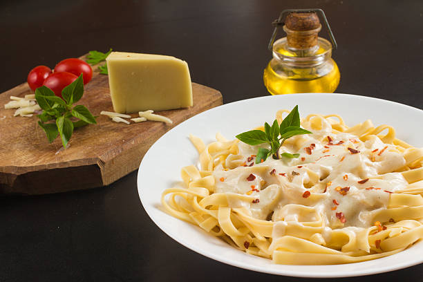 Penne with milk cream Penne with milk cream sauce, cherry tomatoes and basil savoury sauce stock pictures, royalty-free photos & images