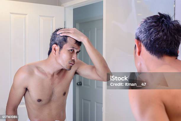 Man Worried About Gray Hair While Looking Into A Mirror Stock Photo - Download Image Now