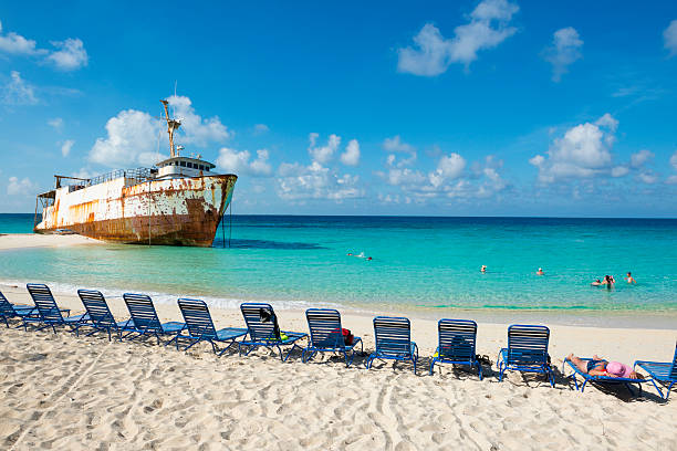 Grand Turk, Turks and Caicos Islands - October 2, 2014: Tourists and a beached ship rest at Governor's Beach on Grand Turk, in the Turks and Caicos Islands.