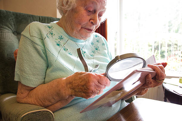 istock Elderly woman using a magnifier to read a book 517170697