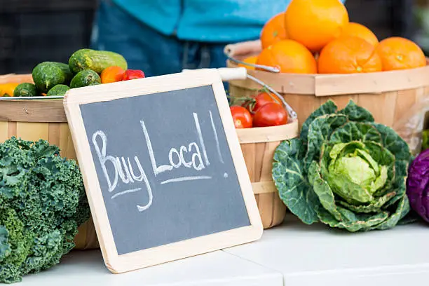 Fresh farmers market veggies with "buy local" chalkboard sign