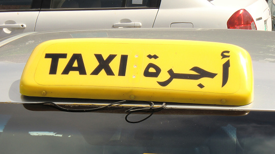 Car-top taxi sign in English and Arabic.  The photo was taken in Abu Dhabi, United Arab Emirates