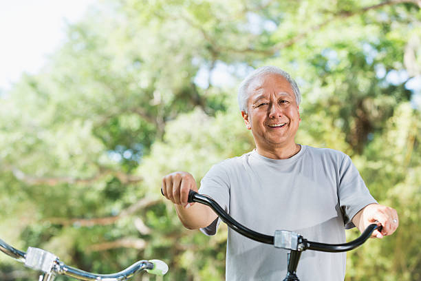 Asian man with bicycle Senior Asian man (60s) with bicycle. man 60s bicycle stock pictures, royalty-free photos & images