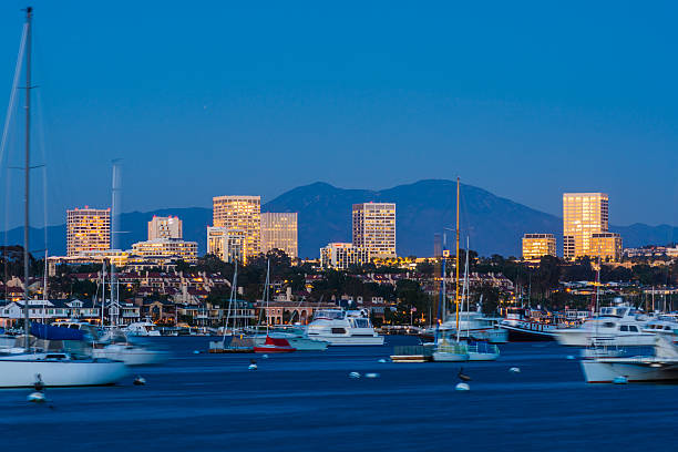 Newport Beach's Fashion Island skyline at dusk Newport Beach’s Fashion Island office district skyline with boats and a harbor in the foreground. newport beach california stock pictures, royalty-free photos & images