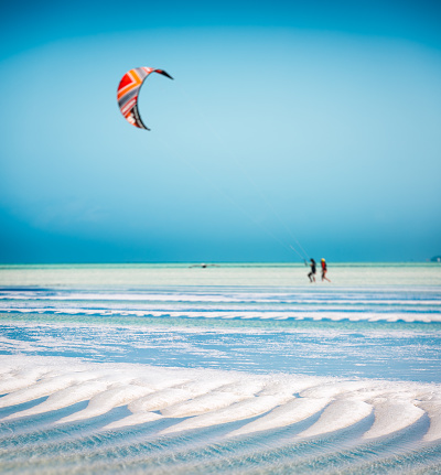 Idyllic sandy beach with turquoise sea (Zanzibar island, Tanzania, Africa). There are kite surfers in the background.