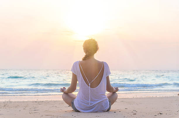 istock woman practicing yoga at sunrise beach 517190792