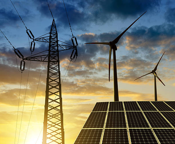 istock Solar panels with wind turbines and electricity pylon 517191300