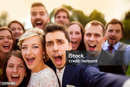 istock Newlyweds with friends taking selfie 517194189