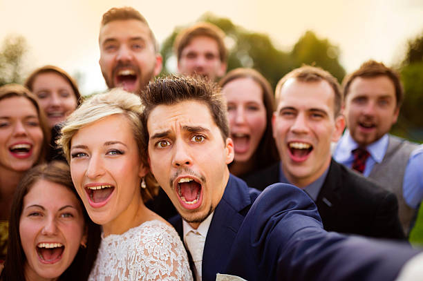 Newlyweds with friends taking selfie Young couple of newlyweds with group of their firends taking selfie and making funny grimaces guest photos stock pictures, royalty-free photos & images