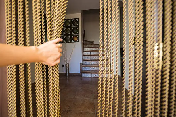A hand opening a beaded fly stopping door curtain in Spain