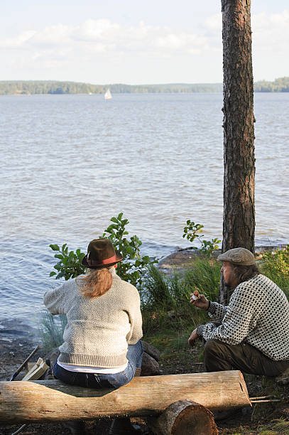 Senior couple by camp fire enjoying lake side view