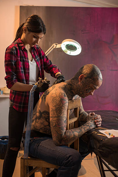 istock Young woman drawing new tattoo on man's back. 517195098