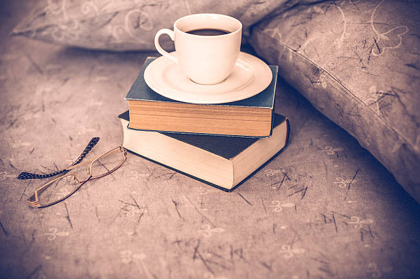 istock Coffee cup, book, reading glasses on bed 517195108