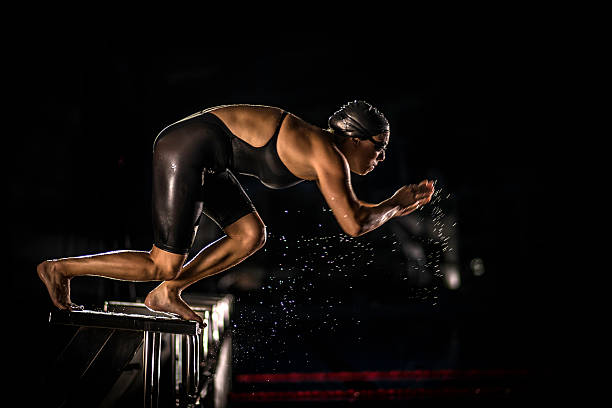 hembra nadador saltando de la el bloque de salida - swimming professional sport competition athlete fotografías e imágenes de stock