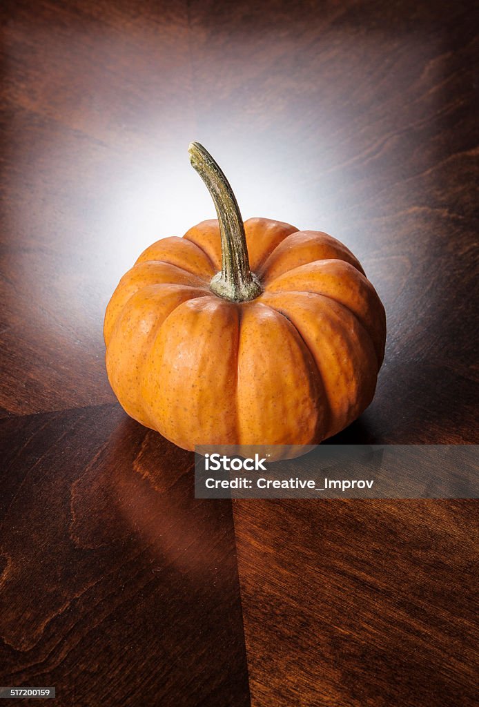 Pumpkin on wooden table Single pumpkin on wooden table with backlighting Agriculture Stock Photo