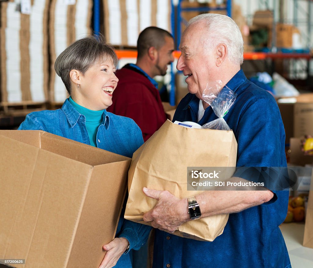 Senior couple donating bags of groceries together at food bank A Helping Hand Stock Photo