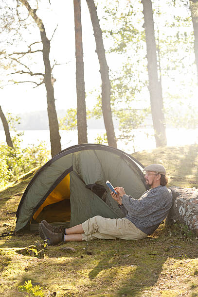 istock Senior man sits outside a tent and reads a book 517201405
