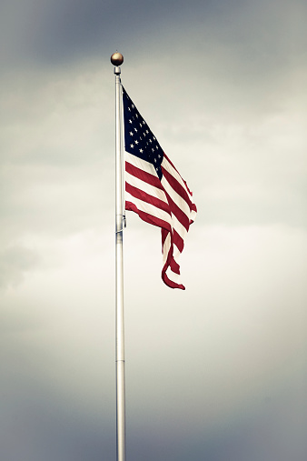 Color picture of the U.S. flag against a cloudy sky.