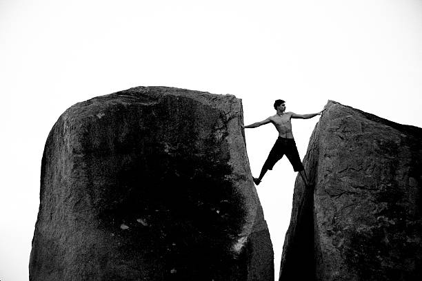 istock Topless Man Climbing Between Two Boulders Black and White 517219621