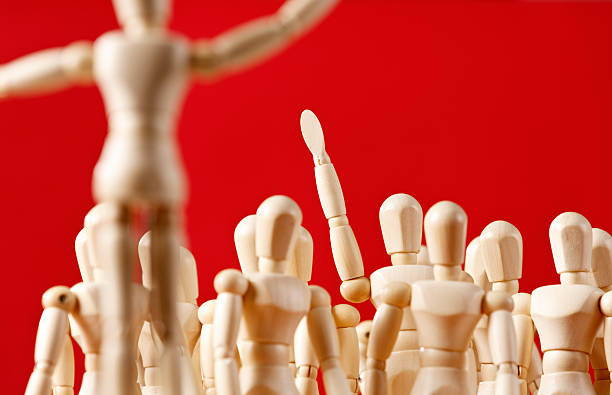 istock Individual puppet in crowd raises hand in response 517220821