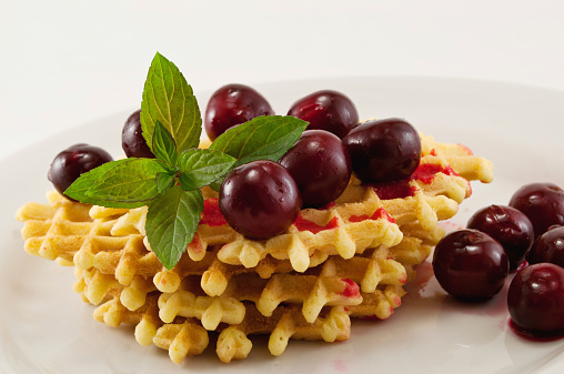 waffles with fresh cherries and mint on a white plate