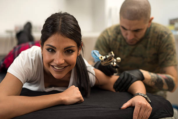Smiling woman getting tattoo and looking at camera.