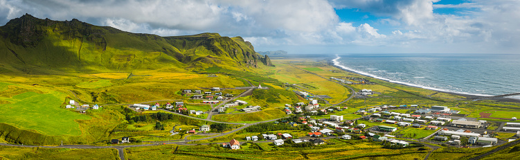 Panoramic view across the rocky valley and green pasture of Vik, the picturesque village nestled beside the ocean in Southern Iceland. ProPhoto RGB profile for maximum color fidelity and gamut.