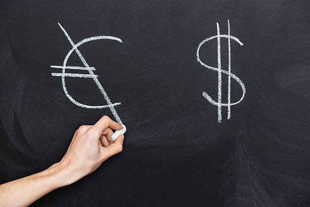 istock Hand crossing dollar and euro signs on blackboard 517223620
