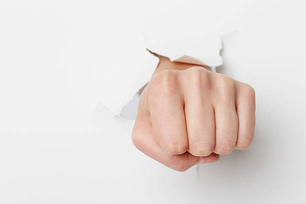 istock Woman's fist breaking through white paper 517224276