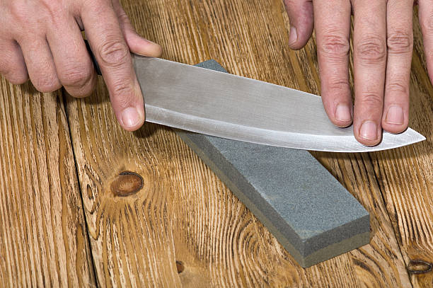 istock Hands sharpening knife and whetstone on  the wooden board 517224282