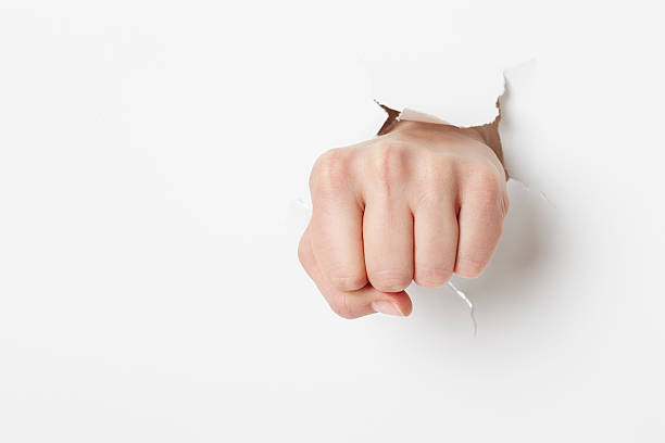 istock Woman punching through white paper 517224324