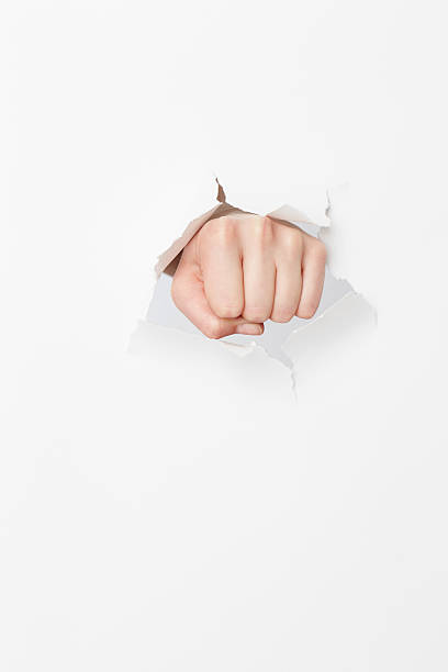 istock Woman's fist tearing though paper 517224370