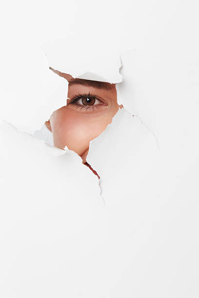 istock Young woman looking through ripped paper 517224634