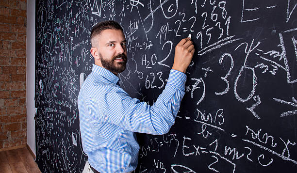 istock Hipster teacher writing on big blackboard with mathematical symb 517224672