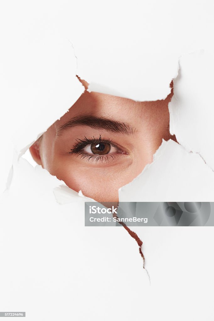 Young woman looking through tears in paper 25-29 Years Stock Photo