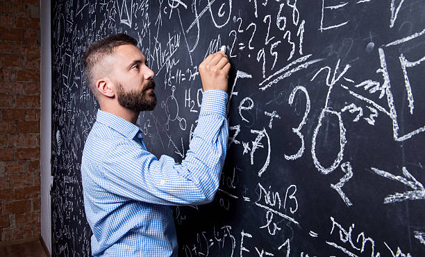 istock Hipster teacher writing on big blackboard with mathematical symb 517224796