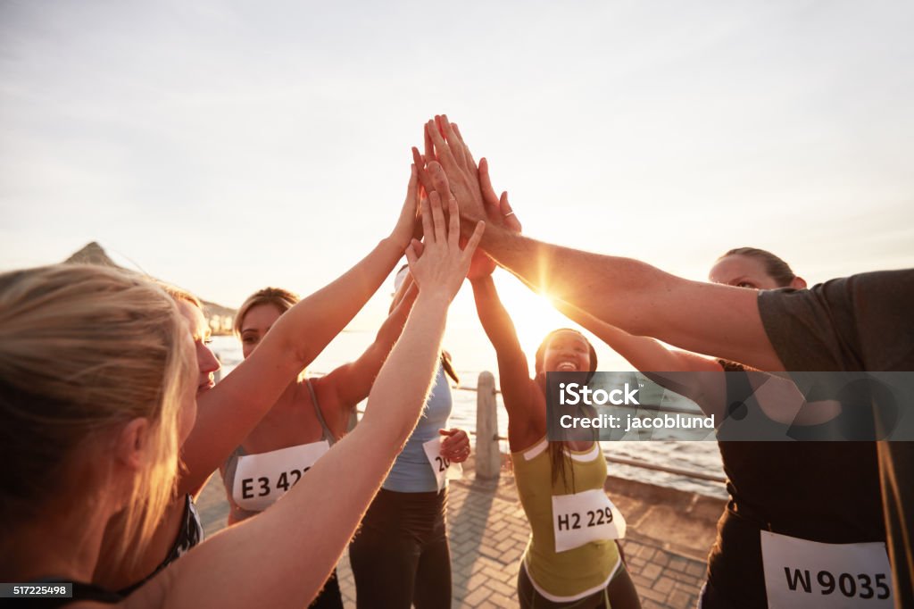 Marathon runners giving high five Athletic team with their hands stacked together celebrating success. Marathon runners giving high five. Sports Team Stock Photo