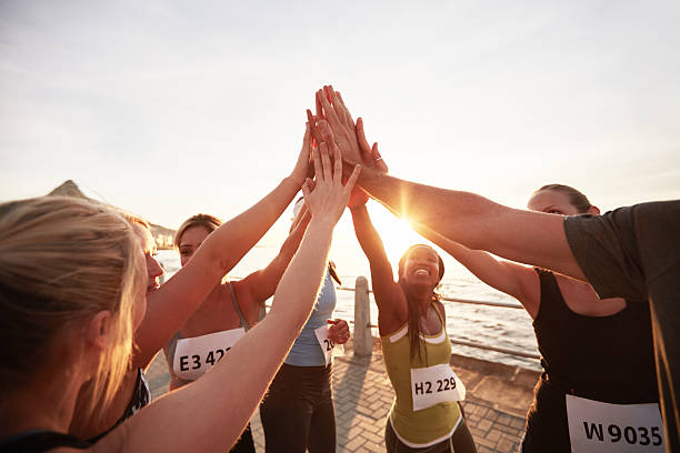 Marathon runners giving high five Athletic team with their hands stacked together celebrating success. Marathon runners giving high five. sports team stock pictures, royalty-free photos & images