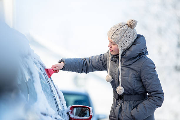 istock Young woman cleaning her car from snow 517228496