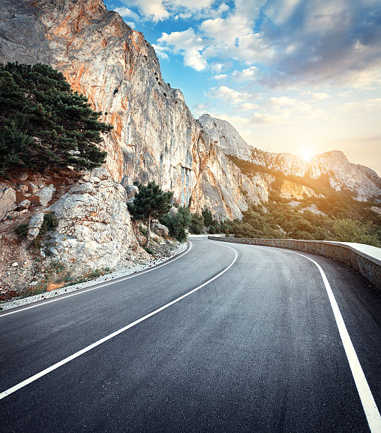 istock Winding mountain road with rocks, blue sky at sunset 517229070