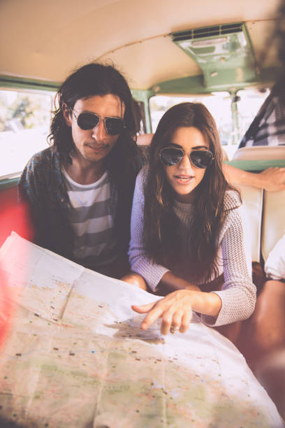 istock Young hipster couple looking at map in vintage van 517232230