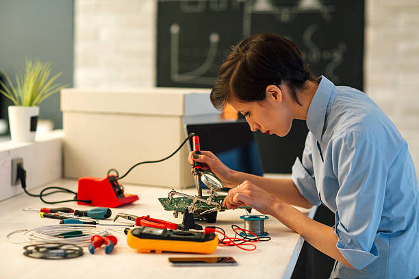 femme à souder un circuit à repasser dans ses tech bureau. - digital voltmeter photos et images de collection