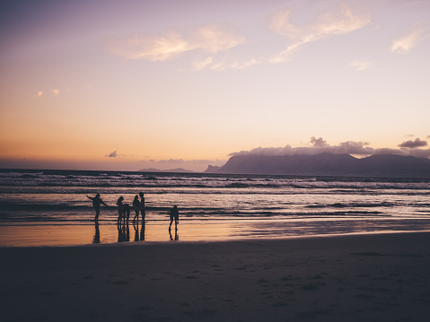 Albion, Mauritius - April 22, 2023: Silhouettes of women and men watching the sunset at the Indian Ocean close the public beach of Albion in the West of Mauritius.