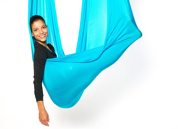 Young woman lying in hammock for anti-gravity aerial yoga stock photo