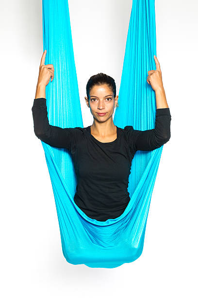 Young woman sitting in hammock for anti-gravity aerial yoga stock photo